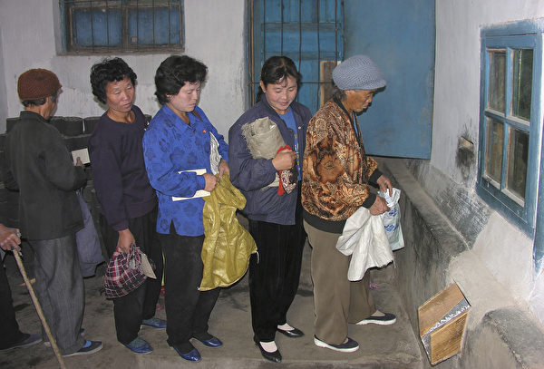 排队领取配给玉米的朝鲜妇人。(Gerald Bourke/WFP via Getty Images)
