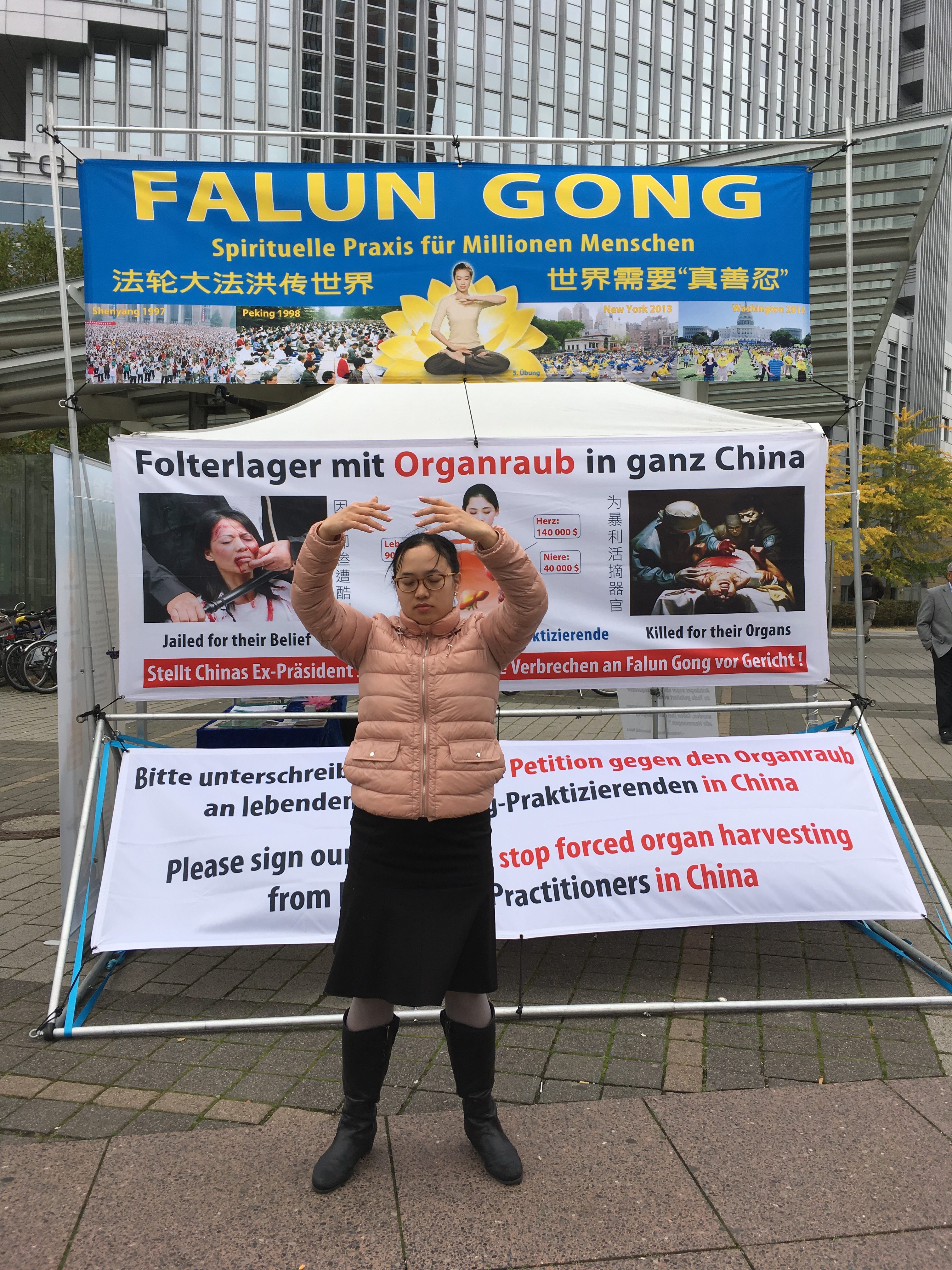 嬅在法轮功咨询展位前炼功。(罗琼/大纪元)