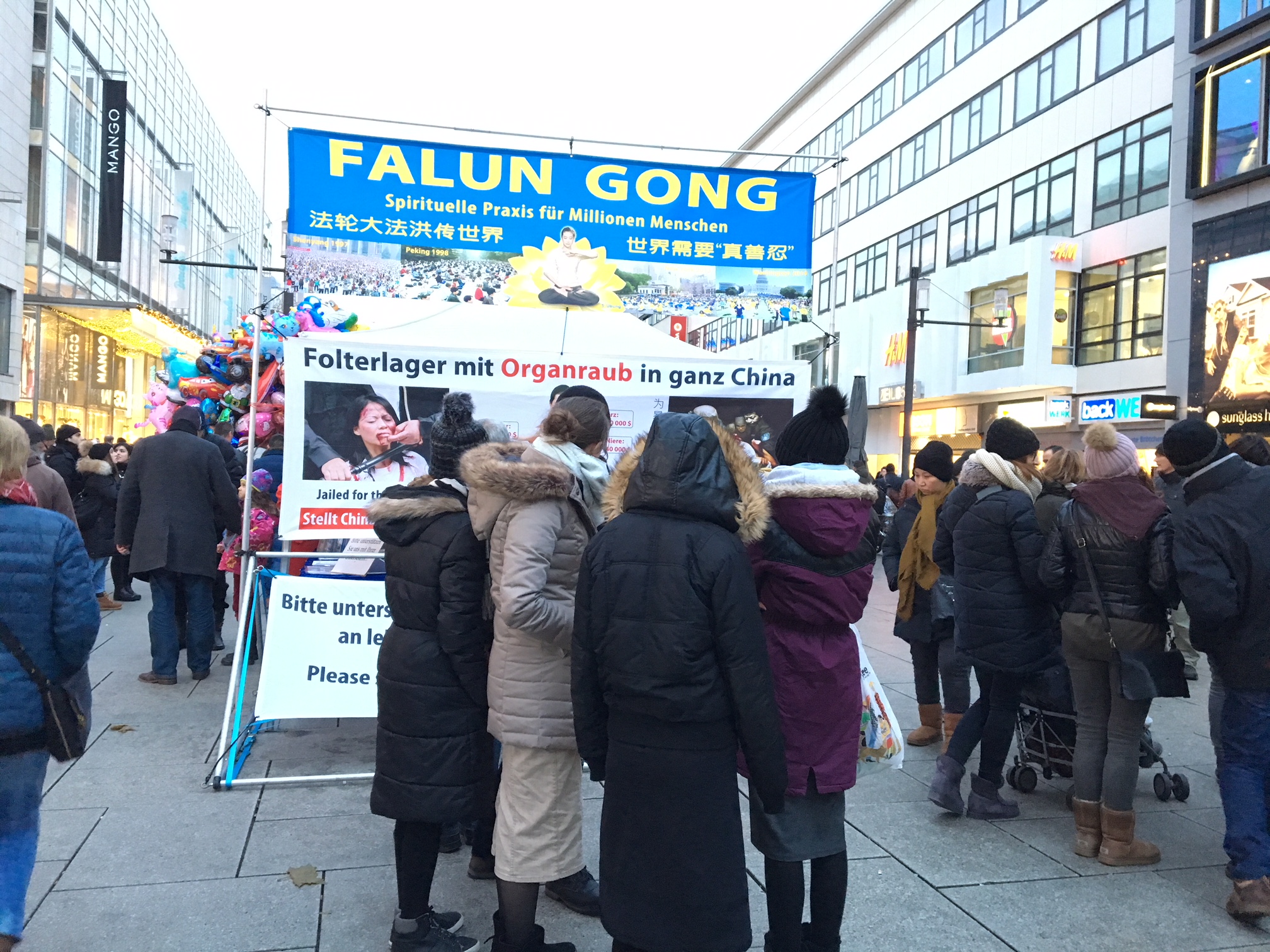 12月9日,人們在法輪功學員搭建的展板前駐足觀看法輪功真相。(羅瓊/大紀元)