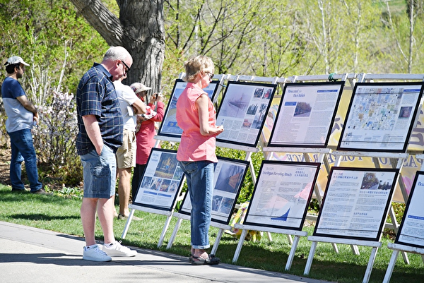 2018年5月13日世界法轮大法日，部分卡尔加里法轮功学员在王子岛公园举行庆祝活动。图为路人驻足观看真相展板。（大纪元）