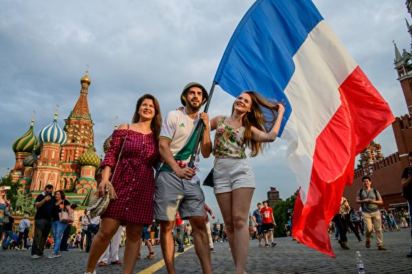 TOPSHOT - France fans hold a French flag as they pose at the Red Square in Moscow on July 14, 2018 on the eve of the Russia 2018 World Cup final football match between France and Croatia. (Photo by MLADEN ANTONOV / AFP)