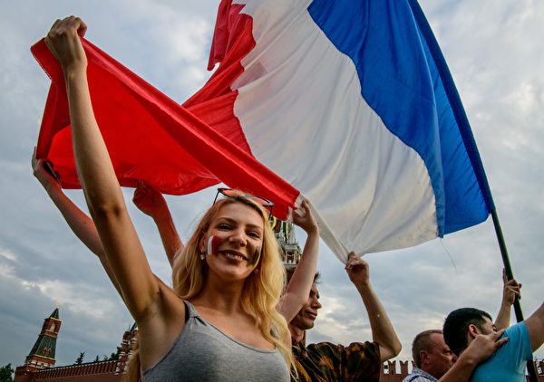 France fans hold a French flag as they pose at the Red Square in Moscow on July 14, 2018 on the eve of the Russia 2018 World Cup final football match between France and Croatia. 