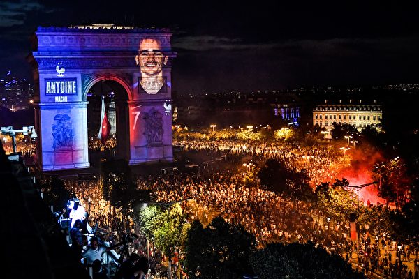 7月15日法国足球队力捧大力神杯，举国欢庆，夜里凯旋门穿上了蓝白红的灯光外衣，法国队队员们的照片也通过灯光投射在凯旋门上。（GERARD JULIEN/AFP/Getty Images）