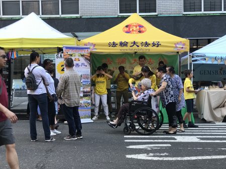 法輪功學員參加了街市節活動，展位跟前吸引各族裔的民眾了解這個東方的中國古老文化——修煉。