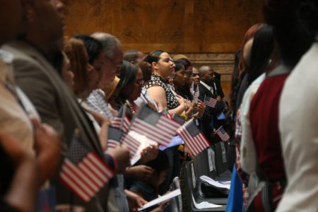 新移民手捂自己的心脏前胸唱美国国歌。