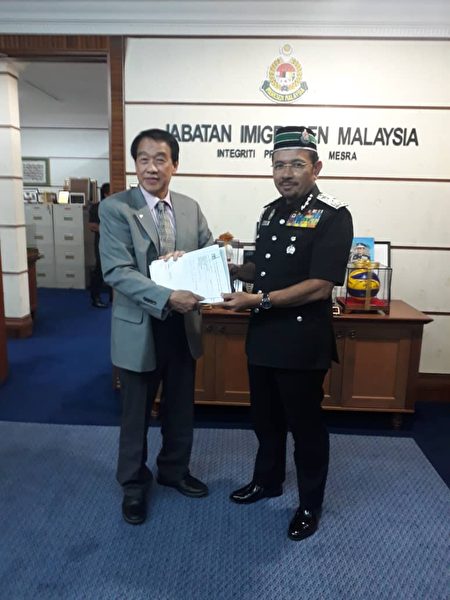 馬來西亞（旅美）聯誼會董事會主席邦君雄（左）向馬來西亞移民局總監（Seri Mustafar Ali，右）遞交反映僑民護照問題的文件。