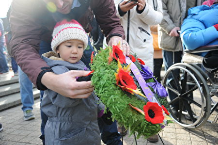 11月11日，本拿比市在南部青年活动中心举行荣军日纪念活动，缅怀为国捐躯的加拿大将士。图为参加纪念活动的儿童献上罂粟花。