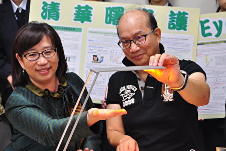 清大教授周卓煇(右)觸摸燭光OLED燈管，證明不會發燙，左為陽明大學護理學院院長劉影梅