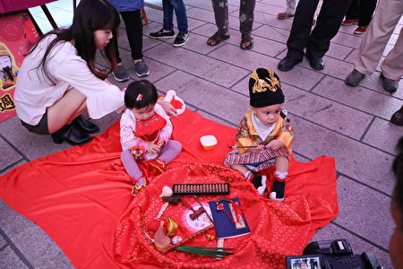  身穿黄帝龙袍的唐齐小朋友(1岁1个月)成为全场焦点，一手抓起象征“学者、教师”的毛笔。