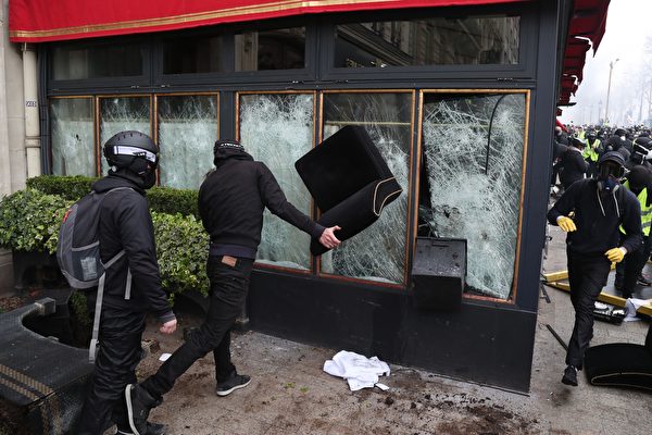 图为身穿黑衣、带黑帽子或头盔且蒙面的破坏者们（casseurs）正在砸毁Le Fouquet's餐厅的玻璃窗。（ZAKARIA ABDELKAFI/AFP/Getty Images）
