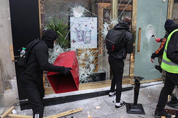 3月16日，在第18轮黄背心示威活动中，身穿黑衣的破坏者（casseurs）正在砸毁商店的玻璃窗。（ZAKARIA ABDELKAFI/AFP/Getty Images）