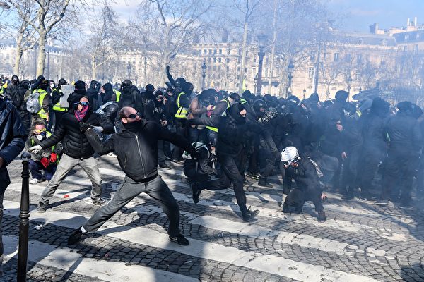 3月16日，在第18轮黄背心示威活动中，许多身穿黑衣者用石头攻击保护凯旋门的宪兵。（ALAIN JOCARD/AFP/Getty Images）