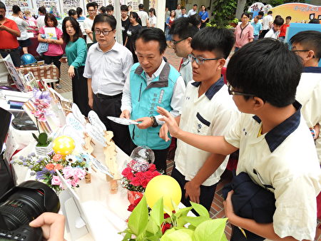 嘉义县长翁章梁（右3）在成果发表会中，用心听布袋国中学生解说创意造型扇子、气球，热升华马克杯的制作要领。