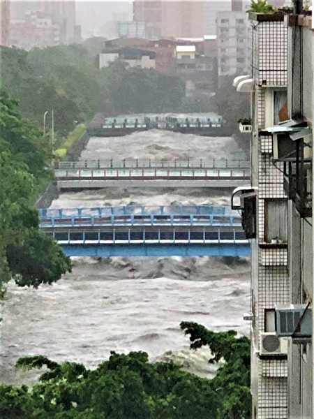 從高處拍下，台中市區麻園頭溪因暴雨，水面暴漲、淹過橋面的驚險畫面。