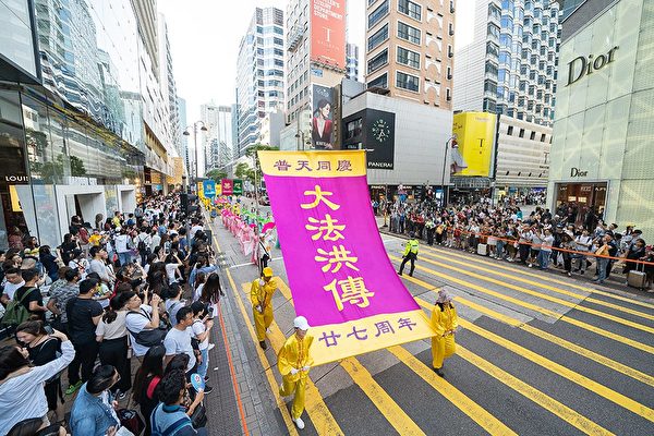 5月12日，香港法輪功學員舉行集會遊行慶祝世界法輪大法日。圖為遊行隊伍途經尖沙咀廣東道，大批遊客和市民夾道觀看，紛紛拍下盛大的遊行場面。（李逸／大紀元）