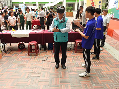 嘉义县长翁章梁（如图）在东吴高职摊位戴上VR，亲自体验玩虚拟实境游戏的乐趣。