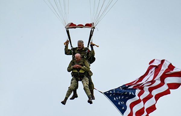 一面美国国旗在二战老兵就是汤姆·赖斯（Tom Rice）身下飘扬。（Ludovic Marin/AFP/Getty Images）
