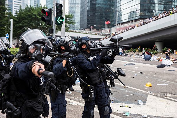 TOPSHOT - Police fire non-lethal projectiles during violent clashes against protesters in Hong Kong on June 12, 2019. - Violent clashes broke out in Hong Kong on June 12 as police tried to stop protesters storming the city's parliament, while tens of thousands of people blocked key arteries in a show of strength against government plans to allow extraditions to China. (Photo by ISAAC LAWRENCE / AFP) (Photo credit should read