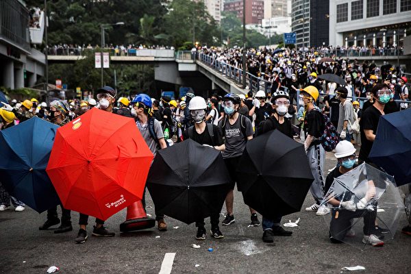 rotesters hold umbrellas to help protect from pepper spray during clashes with police over a controversial extradition law proposal outside the government headquarters in Hong Kong on June 12, 2019. - Violent clashes broke out in Hong Kong on June 12 as police tried to stop protesters storming the city's parliament, while tens of thousands of people blocked key arteries in a show of strength against government plans to allow extraditions to China. (Photo by ISAAC LAWRENCE / AFP) (Photo credit should read