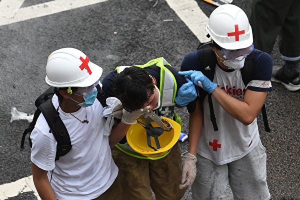 TOPSHOT - A protester is helped by medical volunteers after being hit by tear gas fired by the police during a rally against a controversial extradition law proposal in Hong Kong on June 12, 2019. - Violent clashes broke out in Hong Kong on June 12 as police tried to stop protesters storming the city's parliament, while tens of thousands of people blocked key arteries in a show of strength against government plans to allow extraditions to China. (Photo by Anthony WALLACE / AFP) (Photo credit should read 