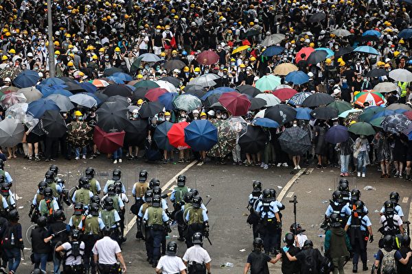 TOPSHOT - Protesters face off with police during a rally against a controversial extradition law proposal outside the government headquarters in Hong Kong on June 12, 2019. - Violent clashes broke out in Hong Kong on June 12 as police tried to stop protesters storming the city's parliament, while tens of thousands of people blocked key arteries in a show of strength against government plans to allow extraditions to China. (Photo by DALE DE LA REY / AFP) (Photo credit should read 