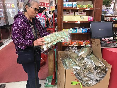  老一辈的华人保留自己在家动手包粽过节的传统，图为端午节当天一名阿婆在超市挑选包粽的竹叶。