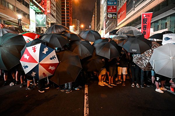 Protesters carry umbrellas to protect themselves as they face the police outside the West Kowloon railway station during a demonstration against a proposed extradition bill in Hong Kong on July 7, 2019. - Tens of thousands of anti-government protesters rallied outside a controversial train station linking the territory to the Chinese mainland on July 7, the latest mass show of anger as activists try to keep pressure on the city's pro-Beijing leaders. (Photo by Hector RETAMAL / AFP) (Photo credit should read HECTOR RETAMAL/AFP/Getty Images)