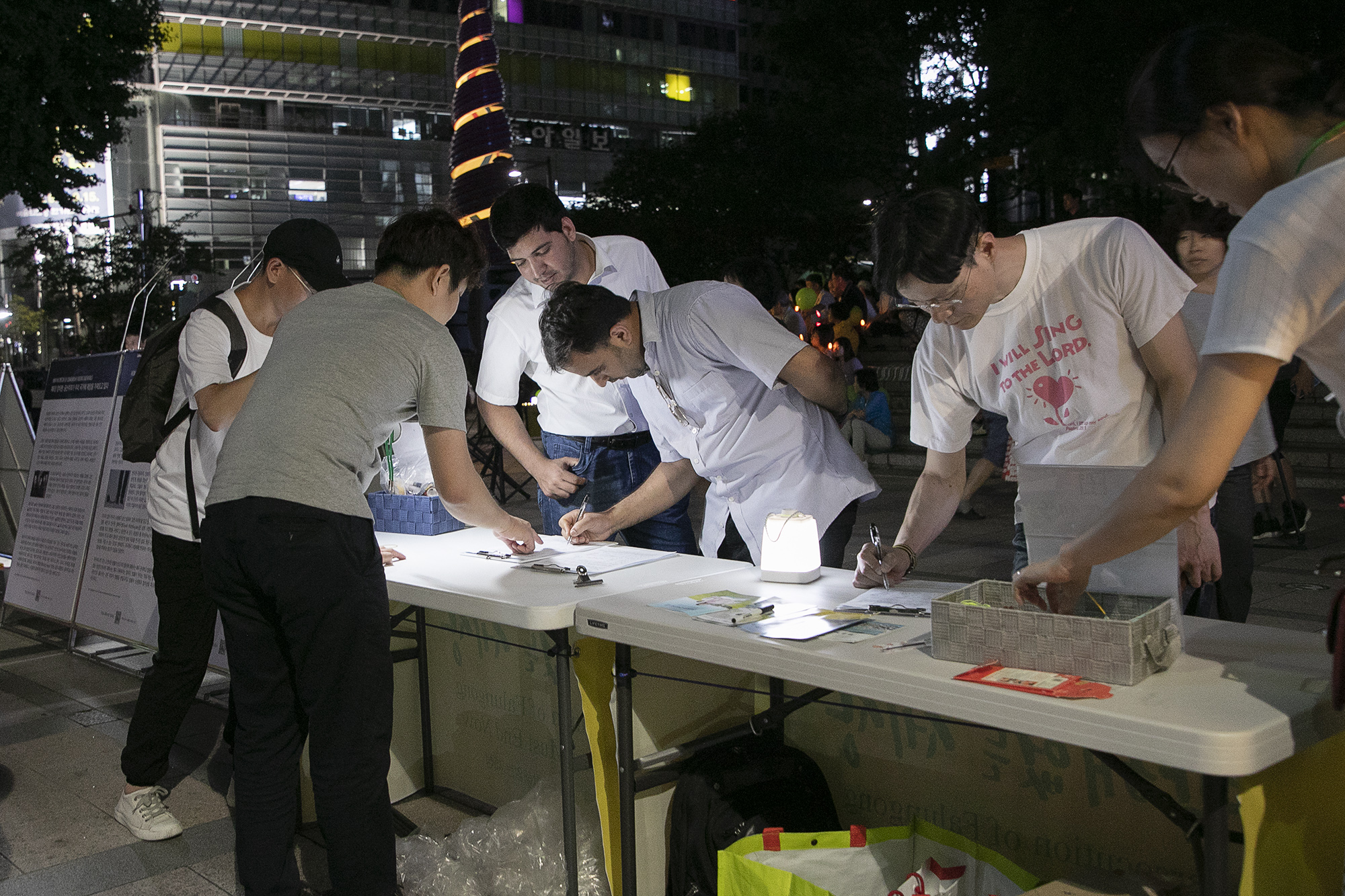 韩国市民和外国游客纷纷在支持反迫害的名单上签字。(全景林/大纪元)