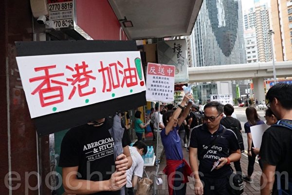 在前往集會地點的路上，有市民舉起「香港加油」和五大訴求的標語。（余鋼／大紀元）