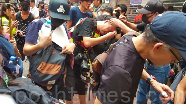 2019年9月29日，「全球連線—共抗極權」遊行活動。港警在銅鑼灣用催淚彈驅散群眾，市民幫記者洗眼。（林志龍／大紀元）