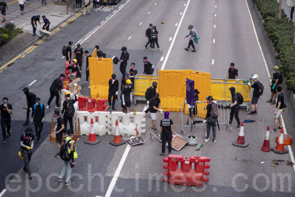 2019年9月29日，全球24個國家、65個城市舉行「全球連線-共抗極權」遊行，圖為香港，遊行隊伍經過灣仔遭遇警方暴力清場，有抗爭者在道路上設置路障。（余鋼／大紀元）