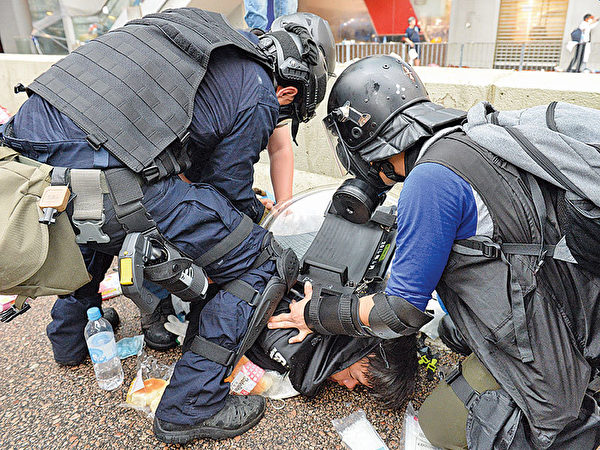2019年6月12日，香港「反送中」示威衝突升高。圖為兩警察把一抗議者臉到壓在地上，很像大陸警察的動作。（宋碧龍／大紀元）