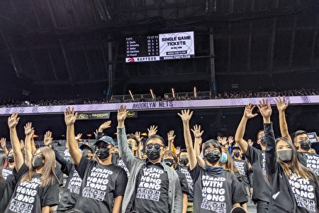 逾150名支持香港人士坐在观众席中，穿着印有“Stand With Hong Kong”的黑色T恤，举起代表“五大诉求、缺一不可”的手势。