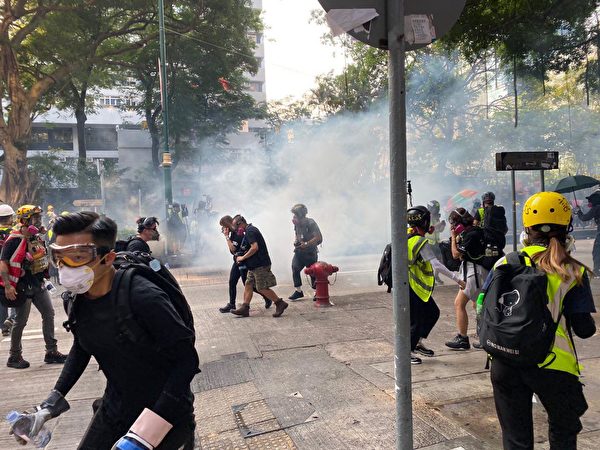2019年10月20日，九龍區大遊行防暴警察向抗爭者發射催淚彈。（駱亞／大紀元）