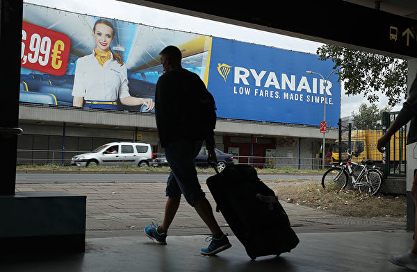 SCHOENEFELD, GERMANY - AUGUST 10: A man pulling a suitcase walks past a billboard advertisement for RyanAir during a 24-hour strike by RyanAir pilots on August 10, 2018 in Schoenefeld, Germany. RyanAir pilots in Germany, Ireland, Sweden, Belgium and Holland are taking part in the strike over demands for better pay and working conditions. (Photo by Sean Gallup/Getty Images)