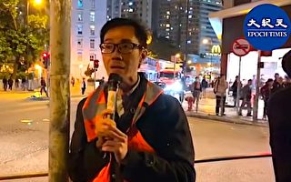 12月6日，周偉雄向記者解釋，在葵青聯校集會有青年因展示「五大訴求 缺一不可」橫額，遭警察帶走（大紀元視頻截圖）