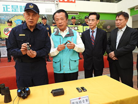 嘉义县警察局长廖宗山（左1）在“查贿制暴”誓师大会中，向与会来宾介绍查贿选作业中所需使用的作业器材。