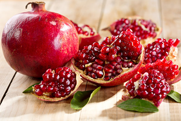 pomegranate with leafs on wooden table Fotolia