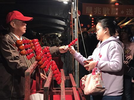 卖糖葫芦的蔡先生(左)说，每年都来年货大街摆摊，享受那年节的喜气。