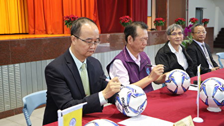  天晴能源股份有限公司董事長葉志忠(左)及民雄農工校長鍾順水(右)在足球上簽名。