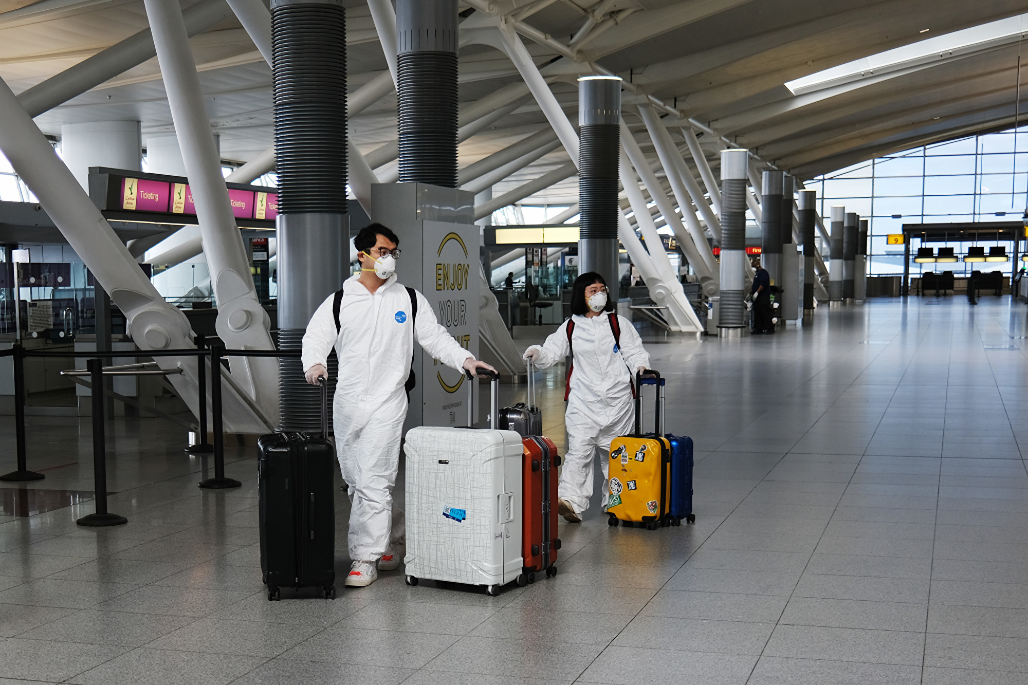 圖為2020年4月16日,旅客穿著防護裝備,步行在紐約市肯尼迪機場(John F. Kennedy Airport)。(Spencer Platt/Getty Images)