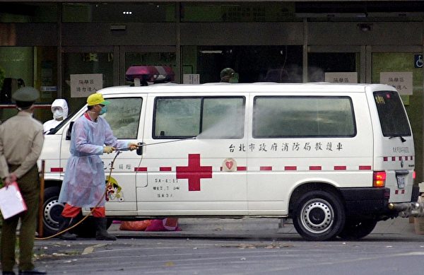 2003年4月，一名男子在台湾三军总医院松山分院门前为一辆运送SARS疑似病患的救护车消毒。(PATRICK LIN/Getty Images)