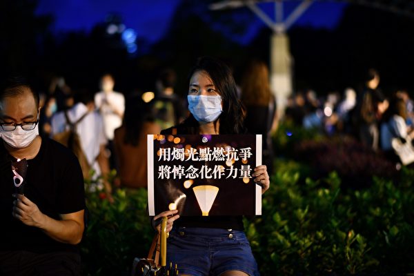 6月4日，香港市民抵达维园，并举起蜡烛悼念“六四”受难者。图中一参与者举着标语。（ANTHONY WALLACE/AFP via Getty Images）