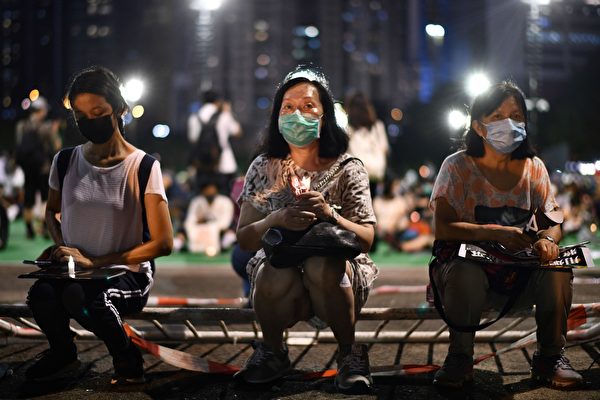 6月4日，香港市民抵达维园，并举起蜡烛悼念“六四”受难者。（ANTHONY WALLACE/AFP via Getty Images）