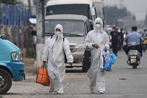 北京疫情嚴重，豐台區已啟動戰時機制；新發地由武警把守，全面封鎖。圖為6月13日，兩女士全身穿防護服走在新發地附近街道。（GREG BAKER/AFP via Getty Images）