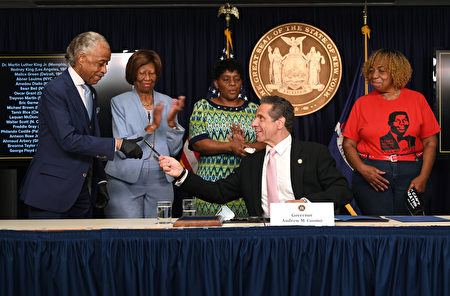 州长库默（左四）将笔交给非裔民权领袖夏普顿（Al Sharpton）。
