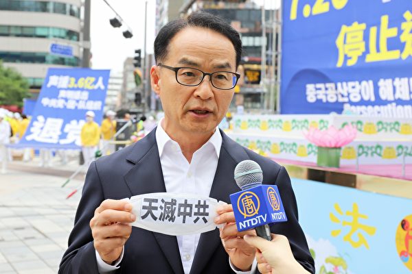 南韓法輪大法佛學會發言人吳世烈在接受採訪時展示貼有標語貼紙的口罩。（金國煥／大紀元）