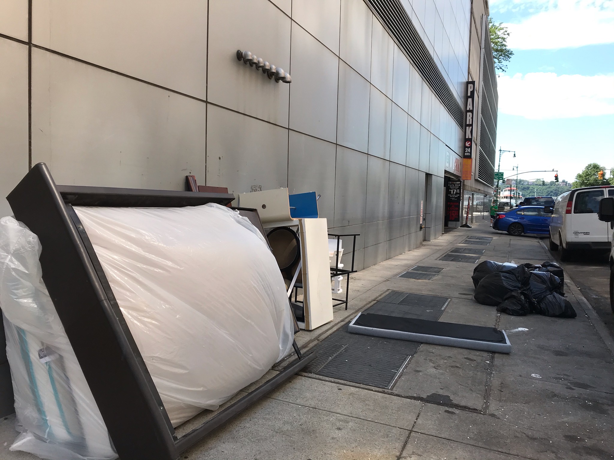 紐約中領館靠43街的停車場出口外,堆置數件丟棄的寢室用品。照片拍於8月3日。(讀者提供)