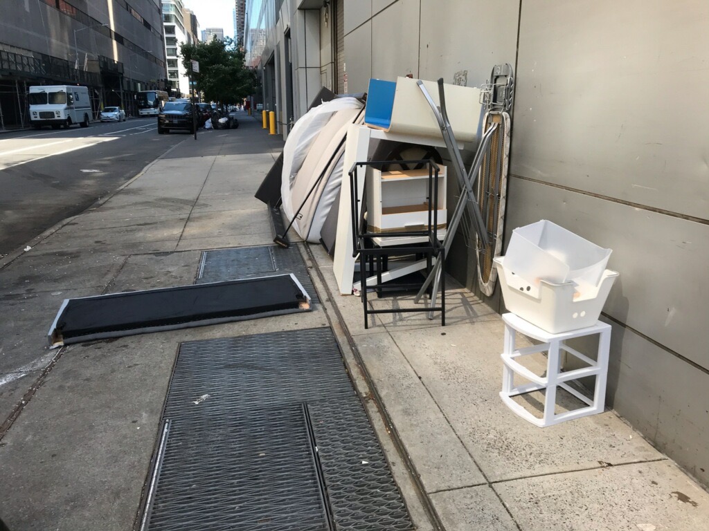 紐約中領館靠43街的停車場出口外,堆置數件丟棄的寢室用品。照片拍於8月3日。(讀者提供)