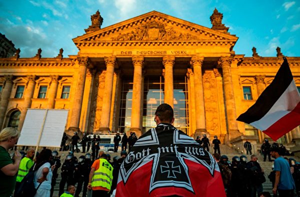 8月29日傍晚，柏林部份示威者聚集在國會大廈前，有人身披德意志帝國旗幟。（JOHN MACDOUGALL/AFP via Getty Images）